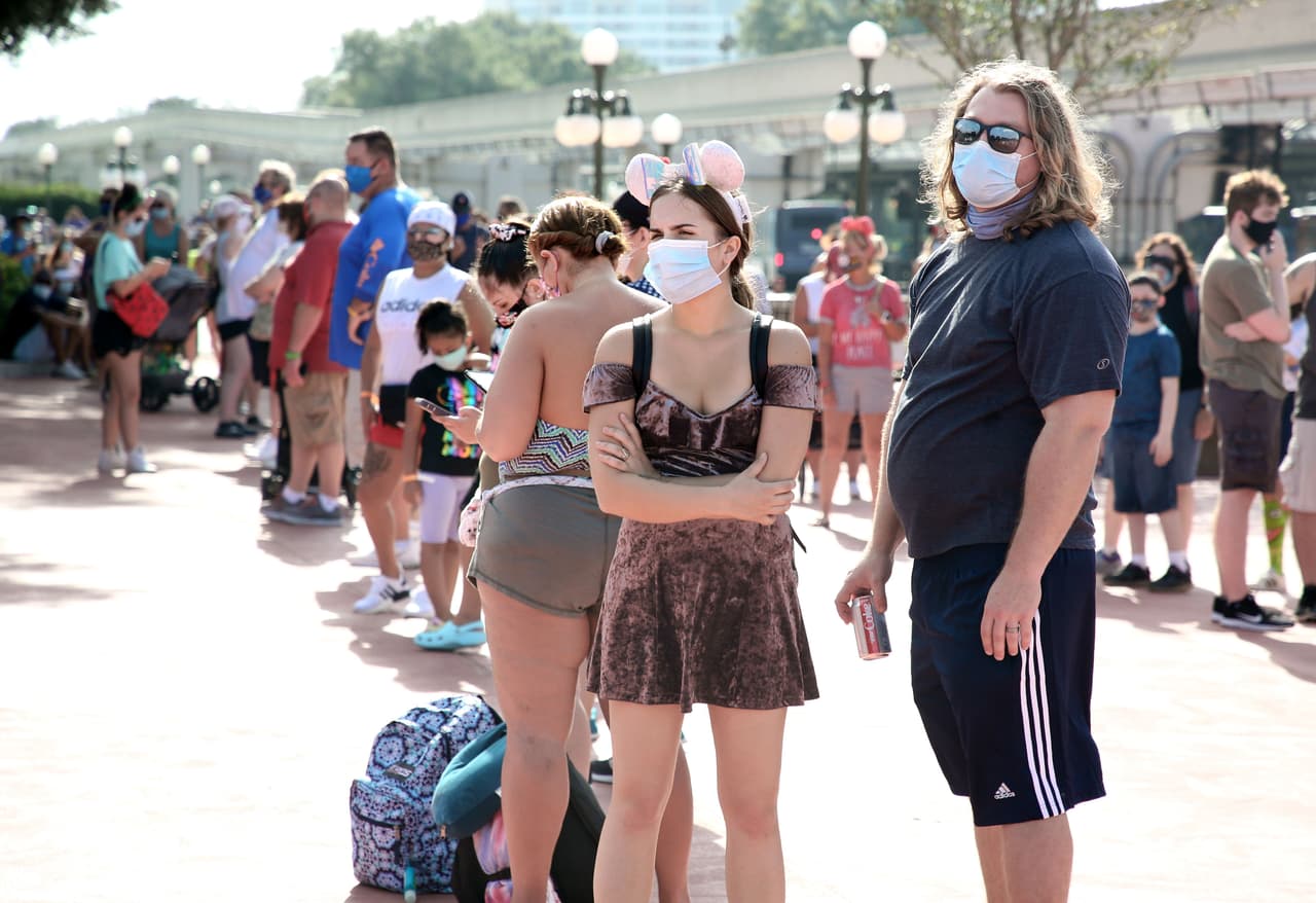 La fila de visitantes enmascarados esperando para entrar a Magic Kingdom. Disney informó que el número diario de turistas está sujeto a límites y que los restaurantes y tiendas, donde "se han incrementado los procedimientos de limpieza", también tienen limitada su capacidad.
<br>