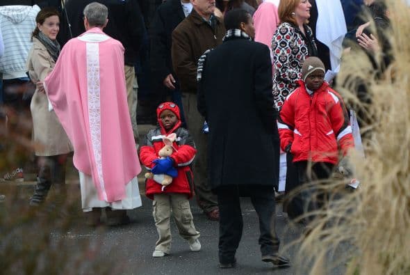 Agentes de la policía del pueblo de Newtown ayudaban a acomodar símbolos religiosos en otro improvisado memorial fuera de la Iglesia Católica de St. Rose de Lima.