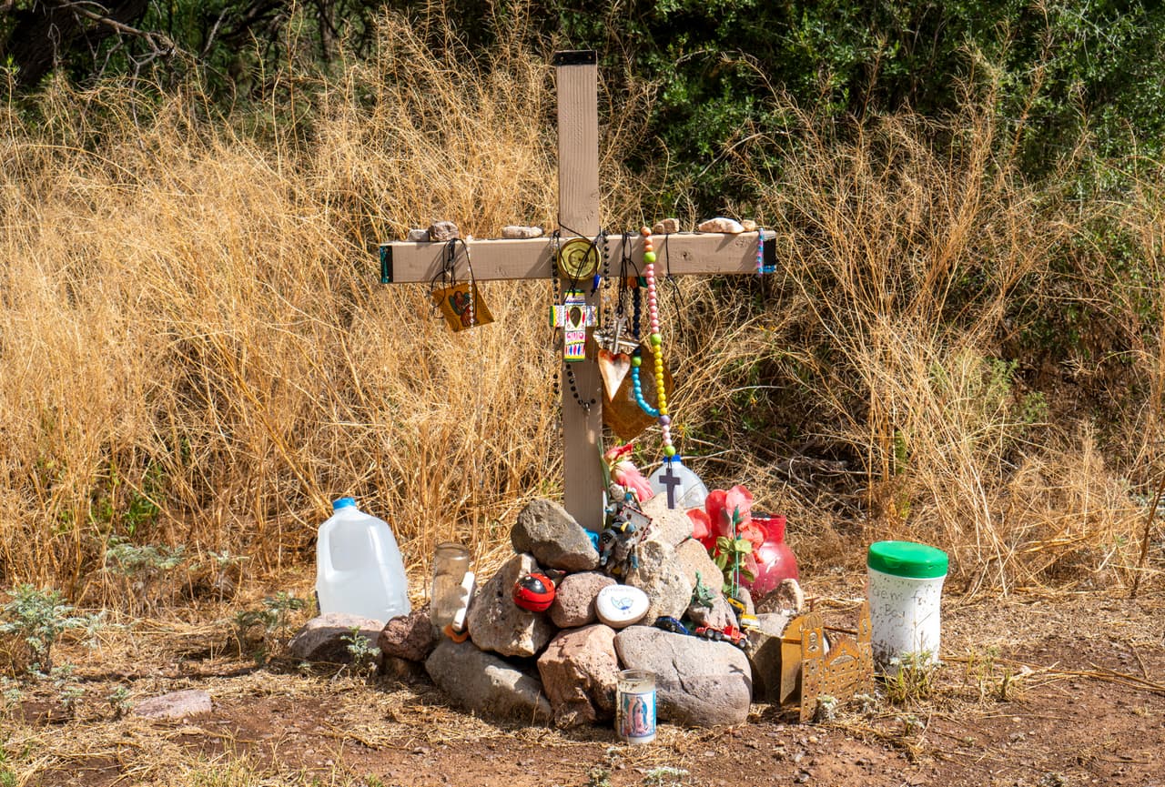 Una cruz de madera con rosarios, cruces de tela e imágenes de la virgen, marca el lugar donde un niño migrante fue encontrado muerto cerca de Arivaca, Arizona.