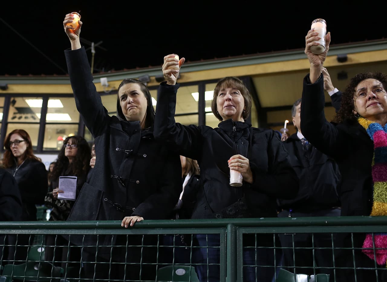 Los participantes de la vigilia en el estado levantan las velas al escucharse la canción "God bless America"