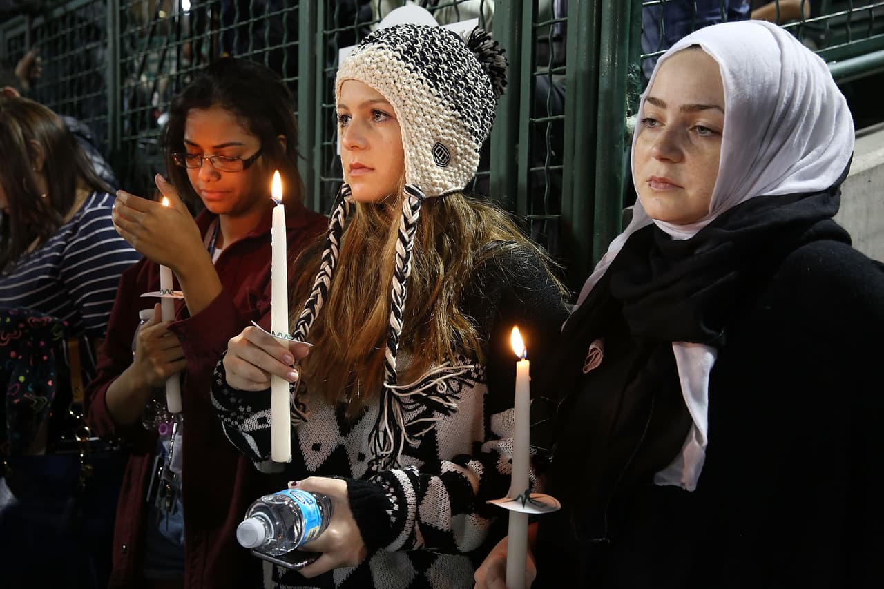 Vanessa Daley, Fatimah Mardini y Najwa Mardini sostienen sus velas en el acto del estadio