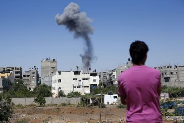Un palestino mira el humo que sale de un edificio tras un ataque aéreo en la ciudad de Gaza.