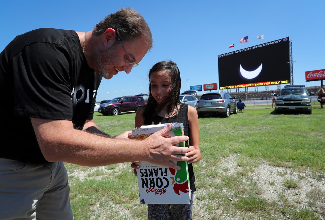 <b>Usando una caja:</b> El presidente del Texas Motor Speedway, Eddie Gossage, disfruta el eclipse utilizando una caja que refleja dentro de sí el avance del fenómeno. Ante la falta de gafas especiales, las cajas improvisadas se convirtieron en una de las formas más comunes para mirar el eclipse. Richard Rodriguez/Getty Images