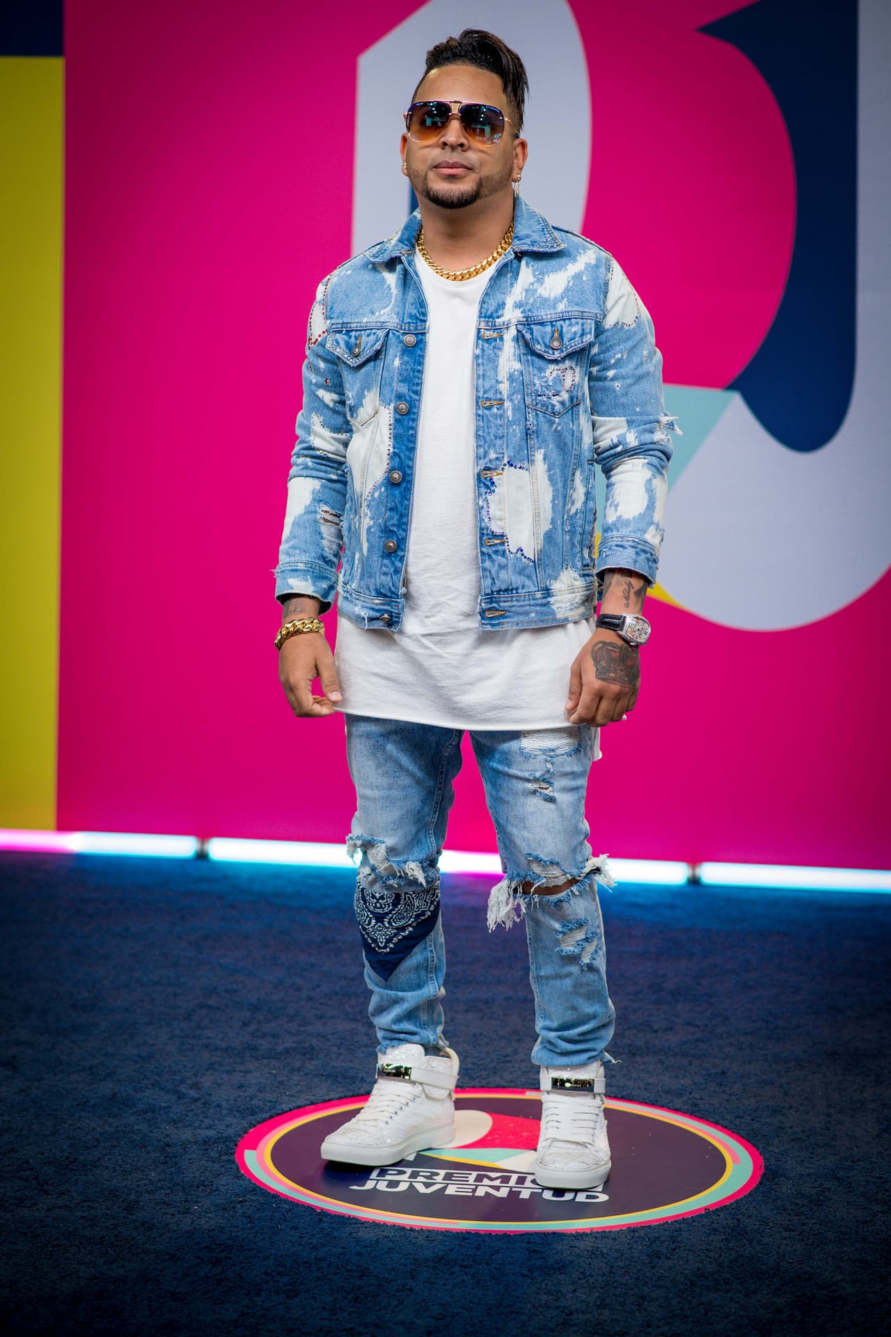 El cubano Yulien tampocó se quedó atrás y llegó a la fiesta musical del verano con un pantalón y chamarra de mezclilla deslavados y rotos. El artista utilizó una bandana en la rodilla derecha y el complemento de su look fueron los tenis blancos Buscemi bordados con lentejuela.