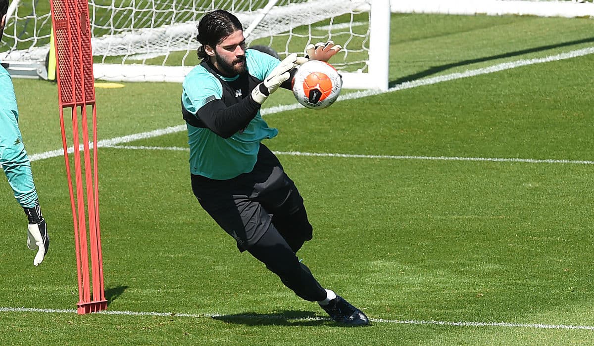 Alisson se lanza por la pelota y cuando la detiene la suelta para correr hacia el otro lado y detener una bola más.