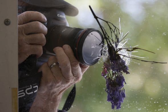 Un hombre toma fotografías de un agujero de bala lleno de flores donde sucedió uno de los ataques de Santa Bárbara.