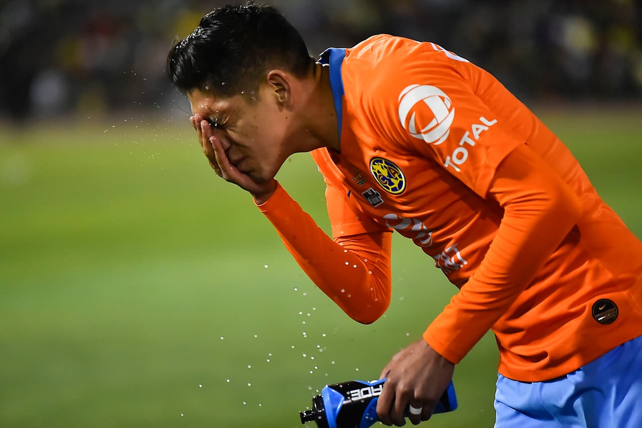 Aquí Edson Álvarez llevándose las manos al rostro luego de un contacto fuerte que le irritó los ojos, por eso se enjuagaba, una señal de lo intenso que estaba resultando el encuentro.