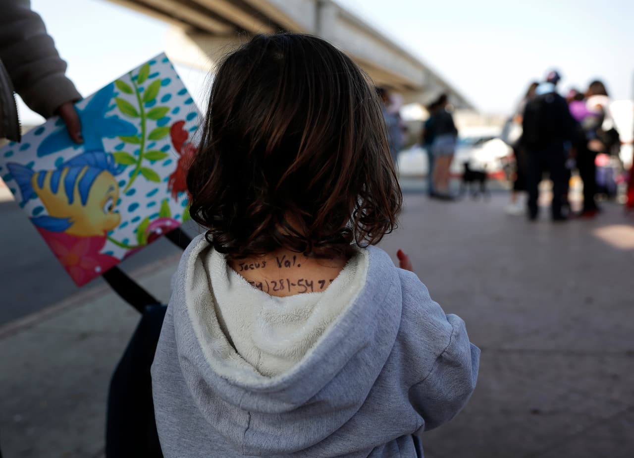 <b>Tijuana, Baja california. Alrededor de 4,800 personas en la lista para solicitar asilo.</b> Esta ciudad, frente a San Ysidro, California, tiene experiencia con el sistema de numeración, establecido cuando en 2016 un grupo de haitianos tuvieron que esperar en por una oportunidad para refugiarse en EEUU.
<a href="https://www.gob.mx/inm/acciones-y-programas/grupos-beta-de-proteccion-a-migrantes"><u>Grupos Beta, una unidad de la agencia de inmigración de México</u></a>, da comida, transporte y ayuda a los migrantes. En la fotografía, una niña mexicana que espera solicitar asilo junto a su madre en Tijuana. Lleva escrito con marcador sus datos personales en la espalda porque su madre teme que podría perderla en el proceso con las autoridades de EEUU.