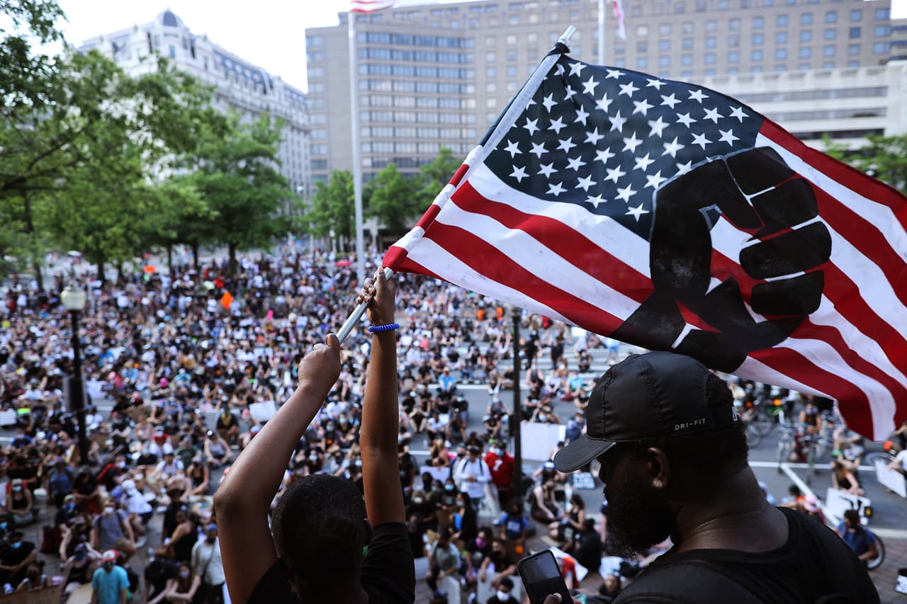 Una manifestante agita una bandera estadounidense hacia una multitud reunida frente al edificio John A. Wilson en Washington DC. En el día 12 de protestas por la muerte de George Floyd, miles manifiestan pacíficamente en la capital de EEUU por los derechos de los afroestadounidenses.