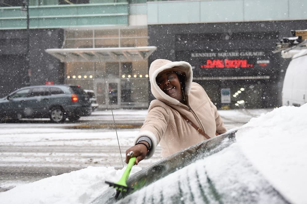 Una mujer limpia el parabrisas de su vehículo en Detroit.