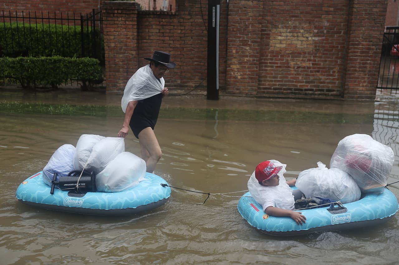 Con sus pertenencias protegidas en bolsas plásticas estos residentes atraviesan una calle inundada en botes de plástico.