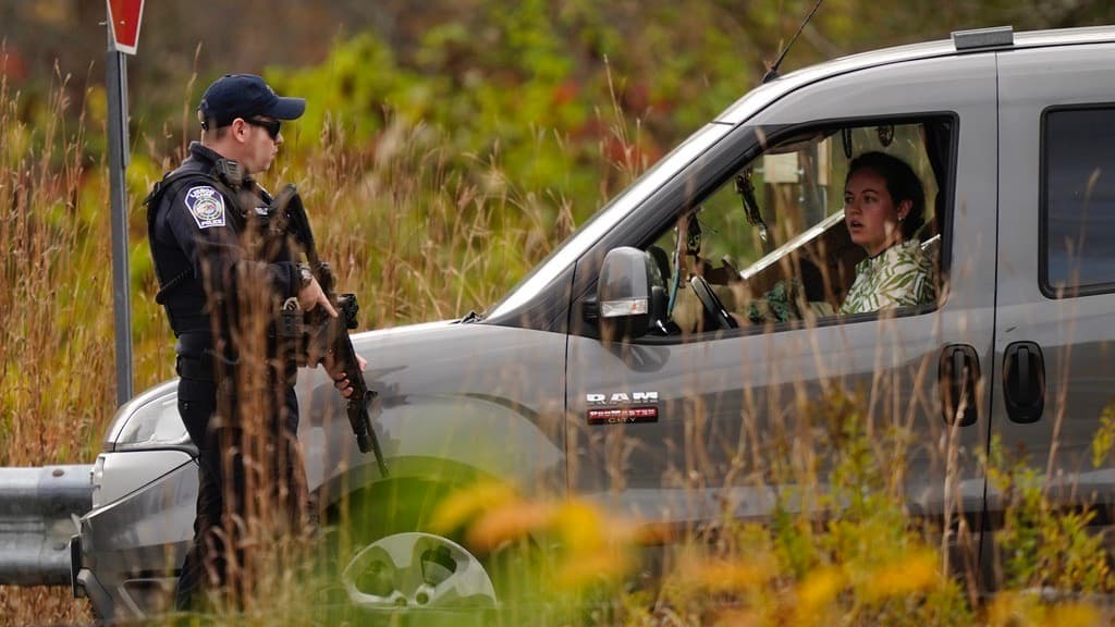 Un agente de policía detiene a una conductora para interrogarla en una alcabala de carretera el jueves 26 de octubre de 2023 en Lisbon, Maine, mientras continúa la búsqueda del sospechoso de los tiroteos masivos que tuvieron lugar en un restaurante y una bolera en la cercana ciudad de Lewiston, Maine.