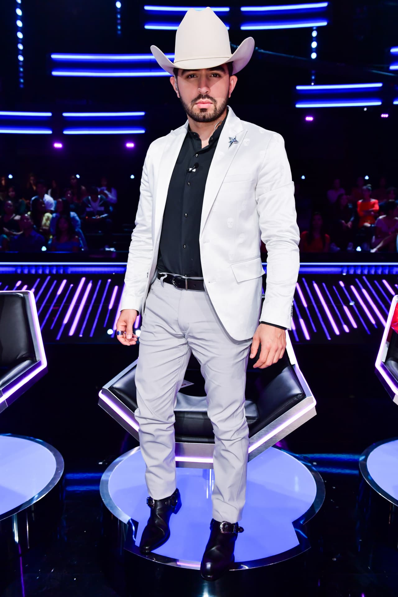 Una vez en su lugar, Joss Favela recuperó su sombrero. En esta ocasión eligió el modelo Stetson El Presidente en color claro, que combinó con un traje gris INC New York, que complementó con una camisa negra. Las botas son de Tom Ford.