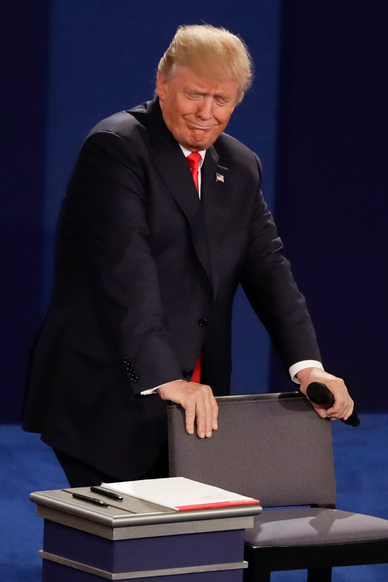 Donald Trump apoyado en el asiento hace un gesto al escuchar una afirmación de Hillary Clinton.