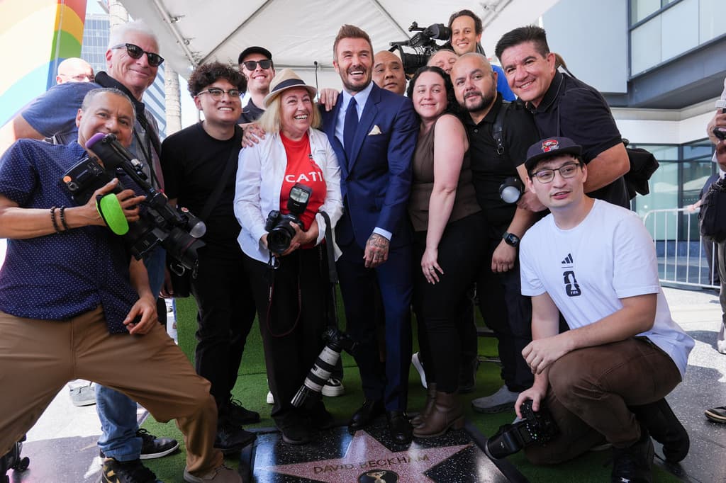 Ya con fotógrafos y camarógrafos ubicados frente al punto del homenaje, Beckham se colocó ante los medios para el primer bloque de imágenes oficiales. La ceremonia avanzó con posados breves y ajustes de protocolo, mientras el área alrededor de la estrella concentró la atención de los asistentes y del equipo de cobertura. En la foto: David Beckham (centro) y miembros de la prensa.