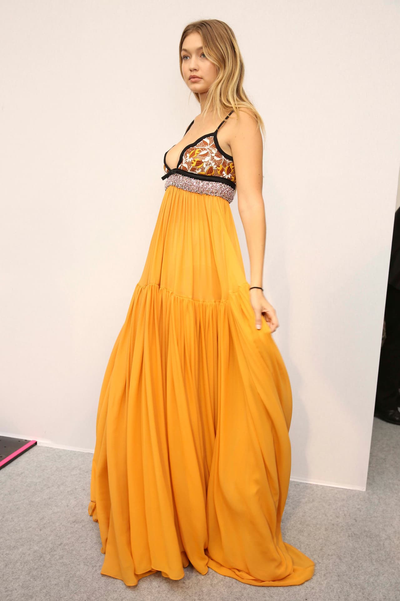 Luego de ser duramente criticada por algunos integrantes del mundo de la moda sobre las curvas de su cuerpo, Gigi se lució en un 'maxi dress' con cuello 'halter' y falda amplia amarilla del diseñador Giambatista Valli. ¡Checa cómo lució!