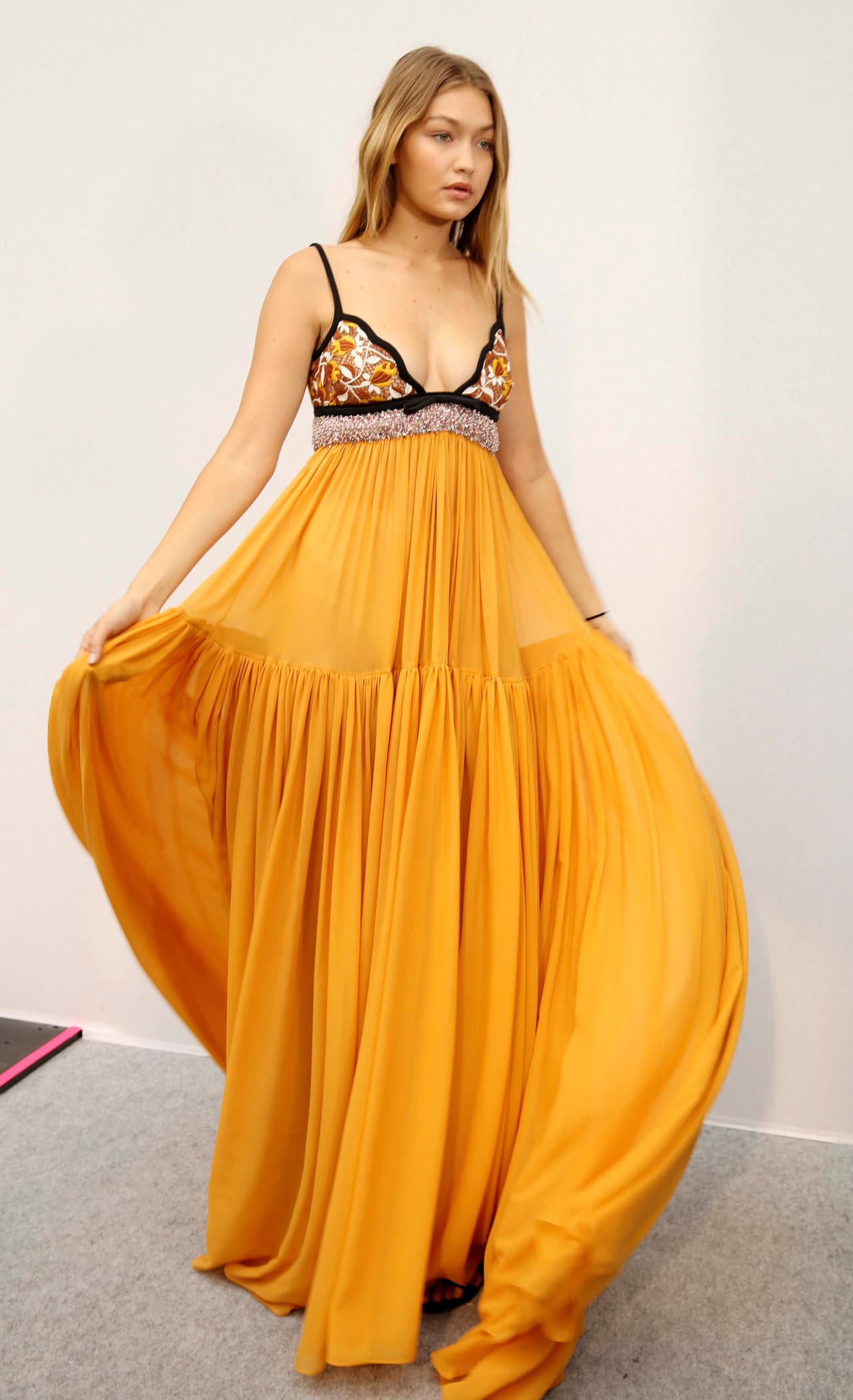 Luego de ser duramente criticada por algunos integrantes del mundo de la moda sobre las curvas de su cuerpo, Gigi se lució en un 'maxi dress' con cuello 'halter' y falda amplia amarilla del diseñador Giambatista Valli. ¡Checa cómo lució!