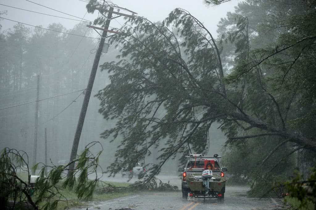 NEW BERN, NC - SEPTEMBER 14: A volunteer rescue truck drives underneath a fallen tree that is suspended by power lines blown down by Hurricane Florence September 14, 2018 in New Bern, North Carolina. Hurricane Florence made landfall in North Carolina as a Category 1 storm and flooding from the heavy rain is forcing hundreds of people to call for emergency rescues in the area around New Bern, North Carolina, which sits at the confluence of the Nueces and Trent rivers. (Photo by Chip Somodevilla/Getty Images)