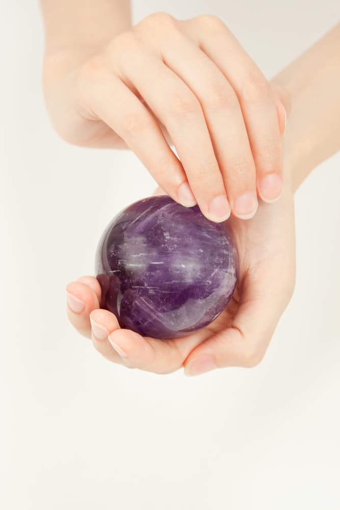 Busca una pequeña piedra o amuleto de amatista, como por ejemplo esta bella esfera hecha con el material. Debes "frotarla" o pasarla por todo tu cuerpo, como si te estuvieras lavando con un jabón o untando crema para el cuerpo.