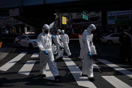 Militares con trajes protectores fumigando las calles de Seúl.