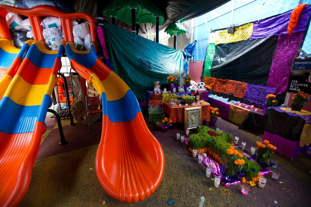 El altar se instaló en el parque infantil del edificio derrumbado en Tlalpan. En los tradicionales altares mexicanos del día de los muertos se colocan ofrendas de comida o los objetos que más valoraban los fallecidos. La madre de Julián y Ximena tiene pensado poner juguetes y golosinas junto a las fotos de sus pequeños.