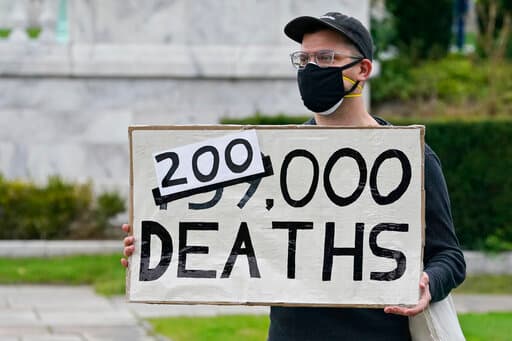 Un hombre sostiene un cartel con el número d muertes por coronavirus en Estados Unidos en un mitin este martes 29 de septiembre de 2020, en Cleveland.