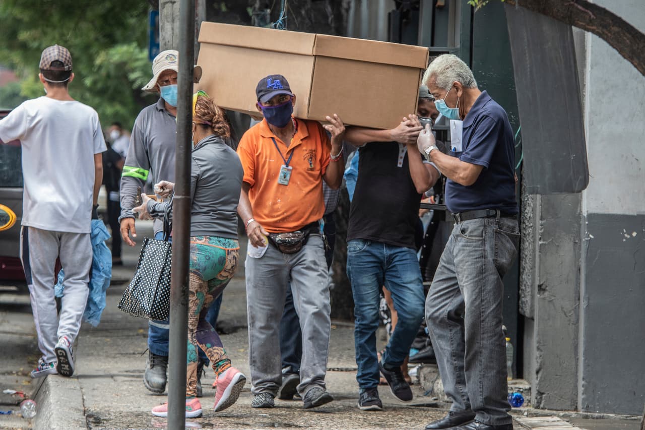 Trabajadores de un cementerio de Guayaquil, Ecuador cargar un ataúd de cartón hecho por fabricantes locales ante el colapso de funerarias y otros servicios en la ciudad.