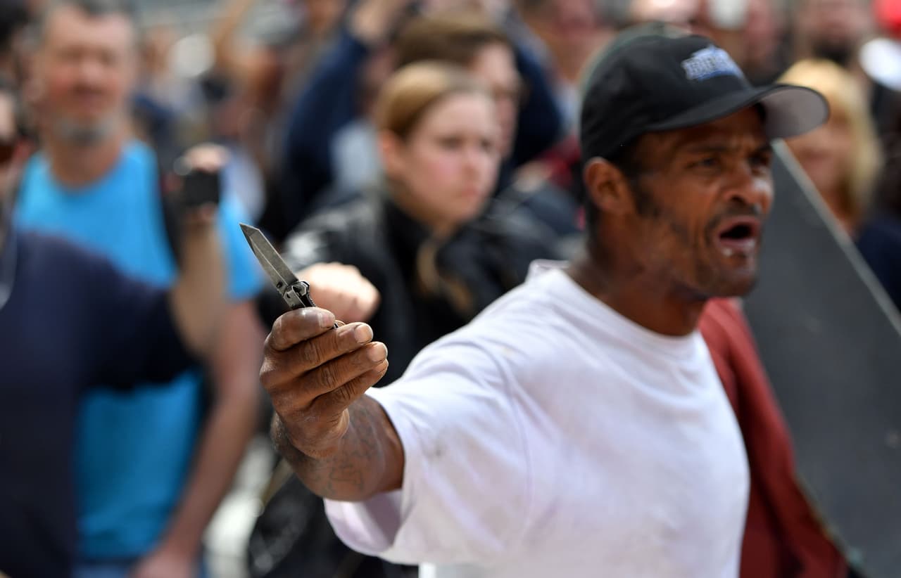 Un hombre muestra una navaja en medio de la multitud.
