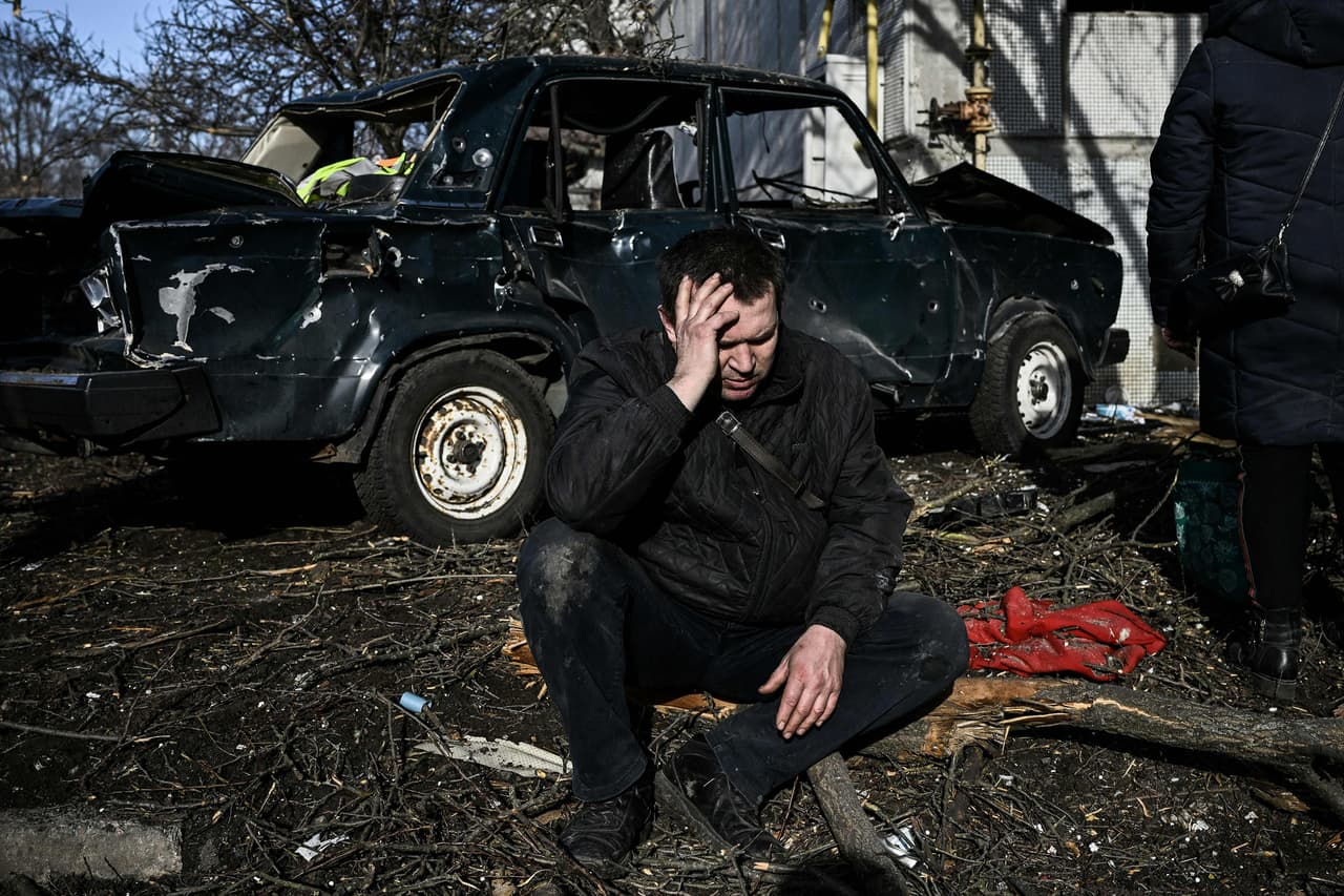 Un hombre frente al edificio donde vivía en la ciudad de Chuguiv, al este de Ucrania, después que fue destruido en los bombardeos rusos del 24 de febrero. Junto a él, fuera del cuadro, estaba el cuerpo de un civil que murió en el ataque
<br>