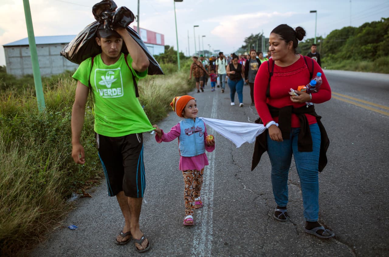 Los hondureños Alejandra Solórzano y Kevin Novoa caminan con su hija Alejandra, de 4 años, cerca de Juchitán, Oaxaca, México. Alejandra se ató a su hija con un trozo de tela para evitar que se pierda entre la multitud. 1 de noviembre de 2018.
