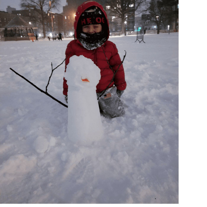Niño hace un muñeco de nieve en el parque Rufus King en Jamaica, Queens.