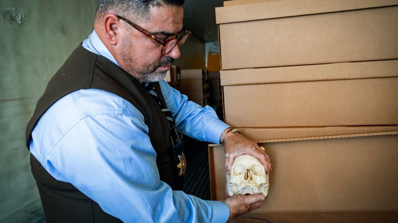 Gene Hernández muestra los restos de un inmigrante que están dentro de las cajas del Médico Forense del Condado Pima, en Arizona.