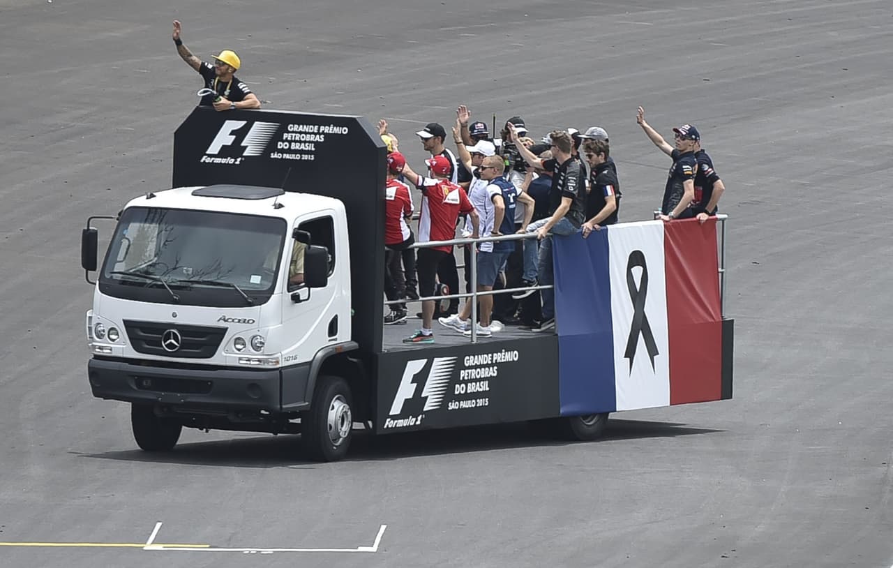 Corredores de Formula 1 desfilan a bordo de un camión con una bandera francesa decorada con un lazo negro en el circuito de Interlagos, en Sao Paulo, Brasil, este domingo.