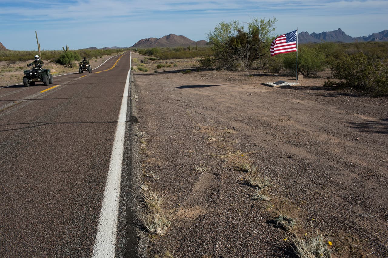 Agentes de la patrulla fronteriza motorizados pasan junto al pequeño monumento en memoria de un compañero muerto en accidente de tránsito cerca de Why, Arizona. 3 de abril de 2017.