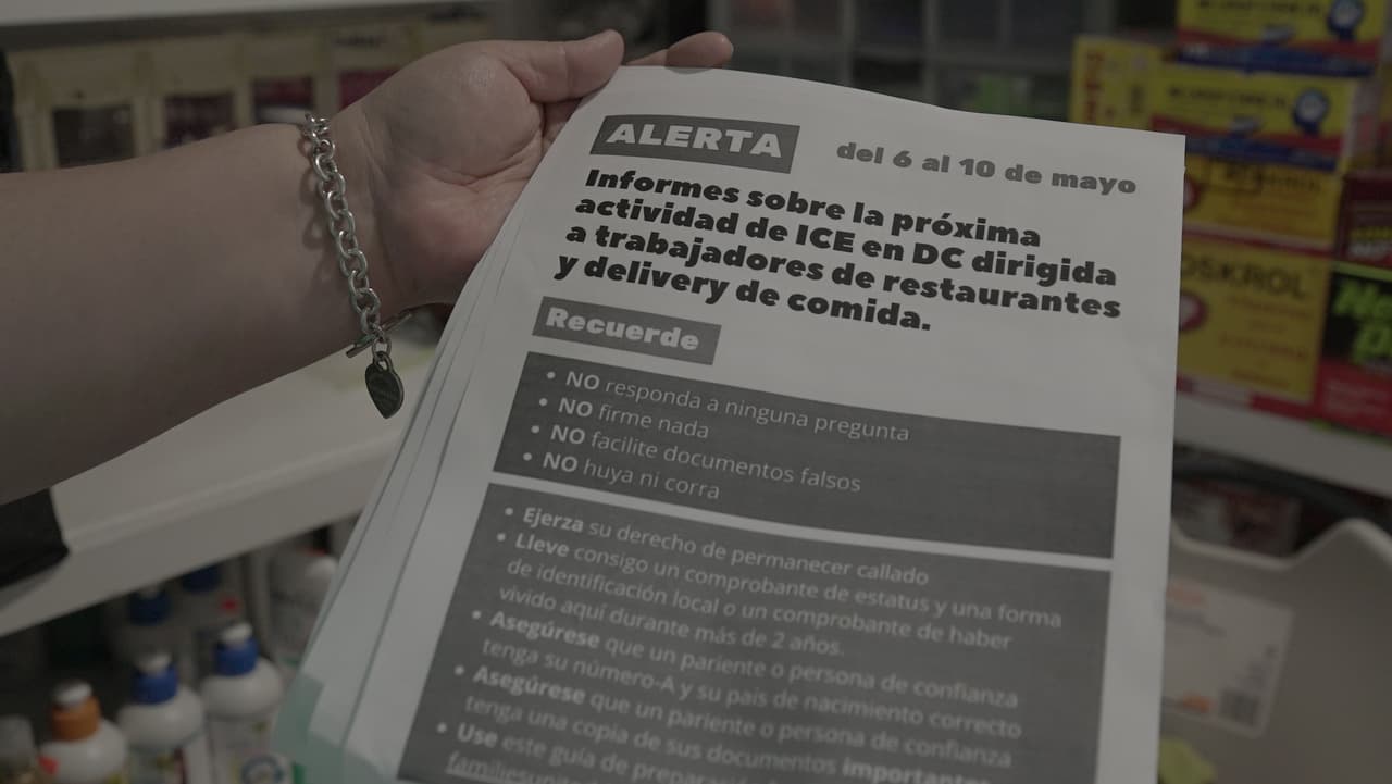 Consuelo muestra un cartel con una alerta para la comunidad sobre la presencia de ICE en distintos negocios.
