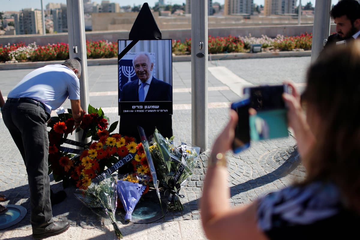 Colocan ramos de flores frente al monolito con la imagen de Shimon Peres