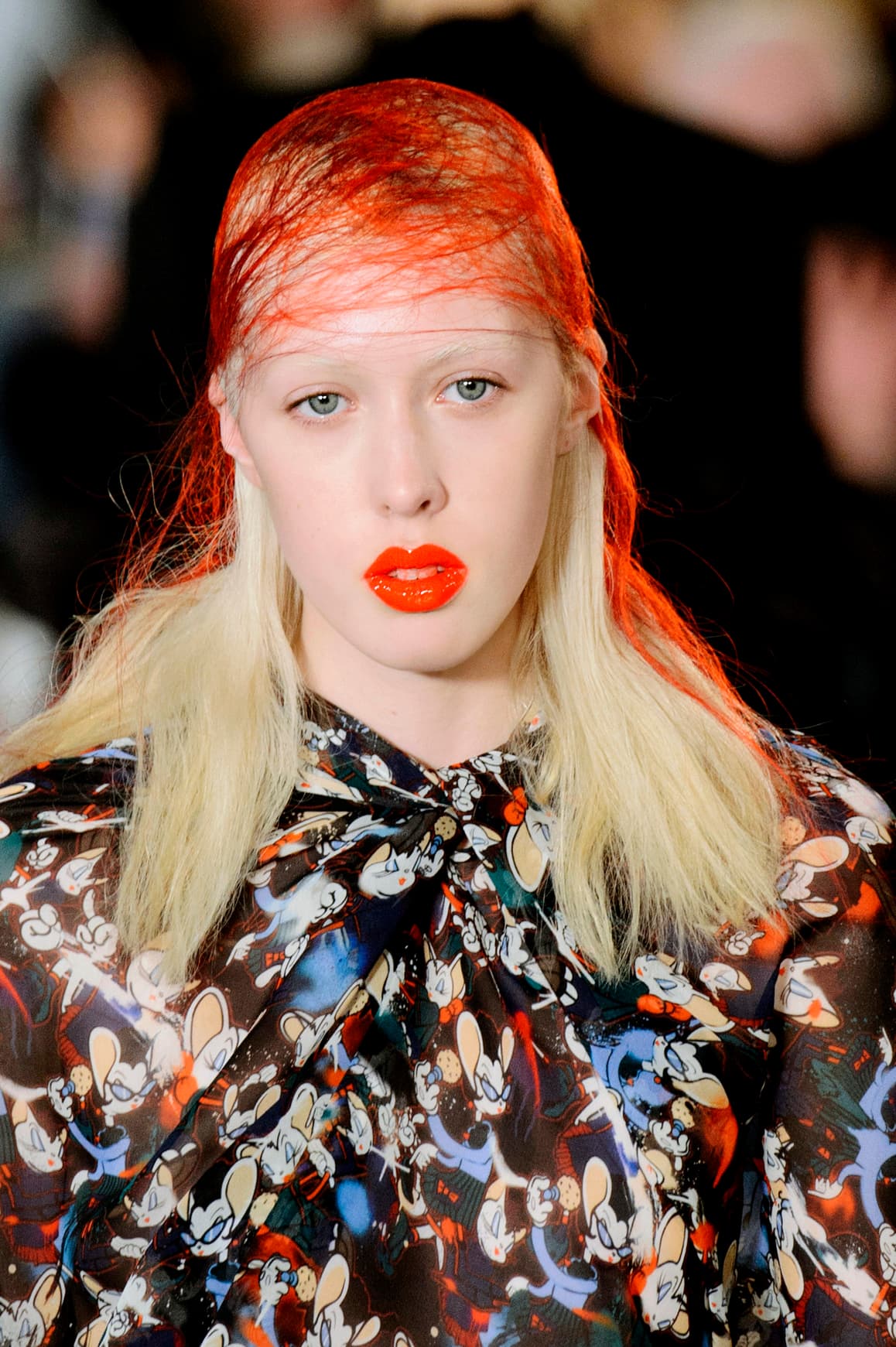 Un rostro con la piel pálida hace que destaquen aún más los labios saturados en tono naranja y con acabado mate; este 
<i>make up</i> es la inspiración perfecta para los que no tienen tiempo —ni ganas— de maquillarse demasiado. La pieza clave para lograr el 
<i>look</i> propuesto por 
<a href="http://www.vogue.com/fashion-shows/fall-2016-ready-to-wear/maison-martin-margiela/slideshow/collection">Maison Margiela</a> es la colorida red. que se coloca sobre el pelo previamente aplacado con gel.
<br>
