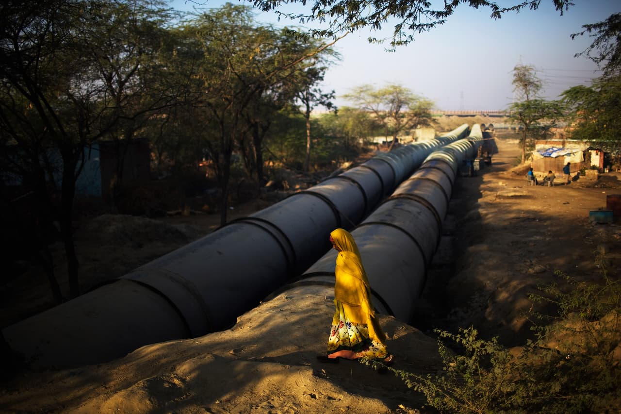 Una mujer pasa junto a una sección de la tubería sin terminar en las cercanías del río Yamuna. En una ciudad de aproximadamente 16 millones de personas, más del 25% de los residentes no tienen acceso a agua potable. Además, se vierten al día unos 950 millones de galones de aguas residuales en el río Yamuna todos los días, el 50% de los cuales entra sin tratar. Según el Banco Mundial, la India se encuentra en una época de grave escasez de agua ya que la población de la ciudad ha crecido más de un 40% en 15 años. Según UNICEF, las enfermedades transmitidas por el agua son responsables de más muertes que el SIDA, la malaria y el sarampión. Daniel Berehulak / Getty Images