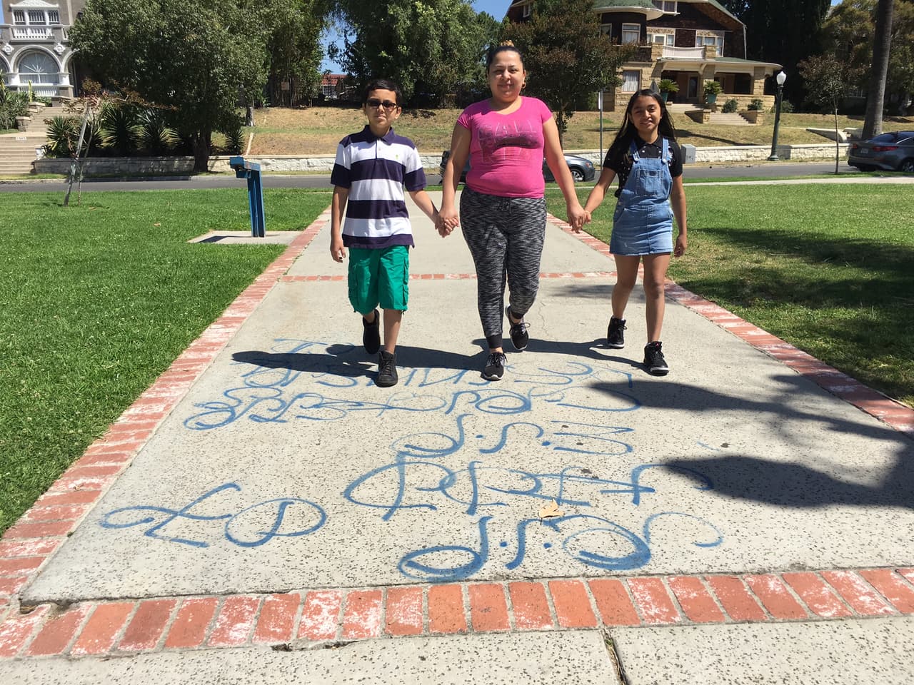 Los niños Arleth y José caminan con su madre en un parque marcado con grafiti de una pandilla en Los Ángeles.