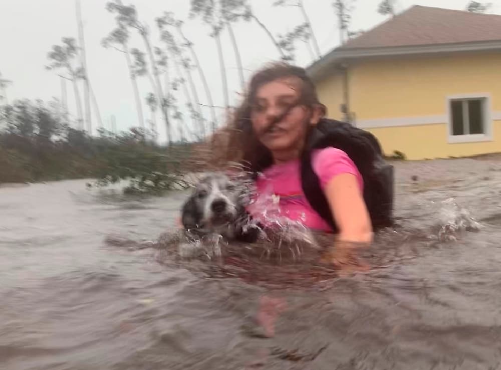Una joven camina con su mascota por una calle inundada de Freeport, Bahamas, el 3 de septiembre de 2019. Con el ojo a 45 millas (70km) de la isla Gran Bahama, Dorian es ahora un huracán categoría 2, con vientos máximos sostenidos de hasta 110 millas por hora (195 km/h).