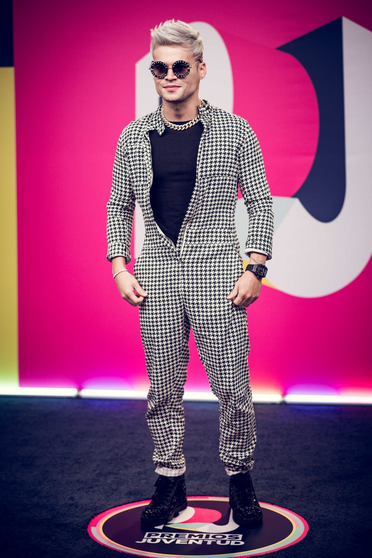 iZaak también demostró que es fan de los tenis, pues el boricua utilizó unos sneakers negros a juego con su jumpsuit con estampado de pata de gallo de Kimbarly Mitch y playera negra. El complemento de su look fueron una cadena dorada y unos lentes de sol Gucci L'aveugle Par Amour.