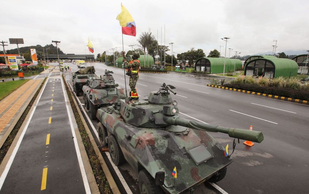 Un soldado levanta una bandera colombiana en un tanque del Ejército en las afueras de Bogotá el 4 de mayo de 2021.
<br>