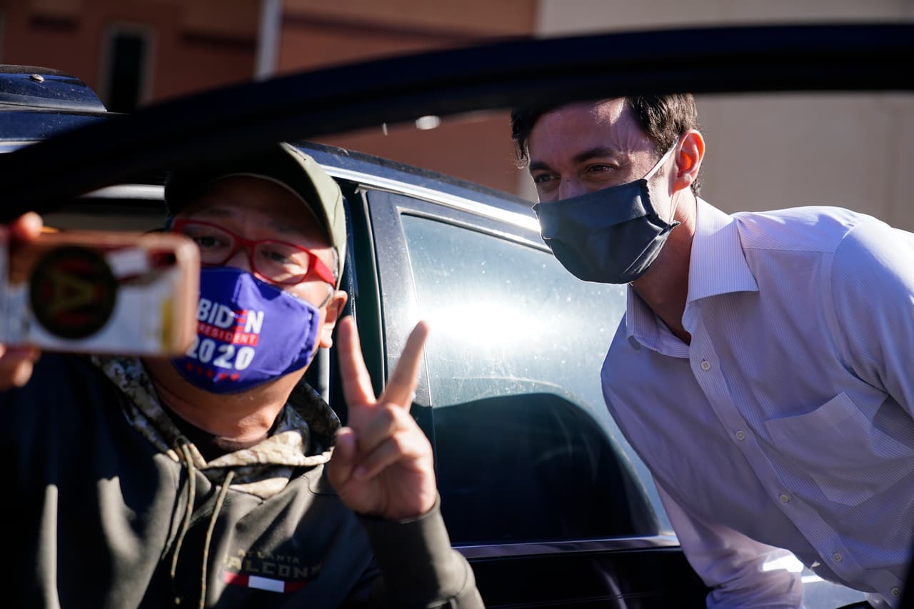 El candidato demócrata de Georgia para el Senado de EEUU Jon Ossoff se toma una selfie con un partidario durante un evento de recogida de letreros el 18 de noviembre de 2020, en Marietta, Georgia. 
<br>
<br>Ossoff y el candidato republicano al Senado del Senado David Perdue se enfrenan en una segunda vuelta para el escaño del Senado.