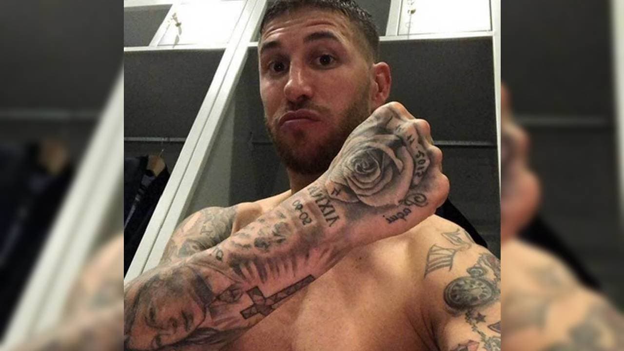 En el brazo derecho luce un rostro femenino y una cruz, además de la famosa rosa en el puño.