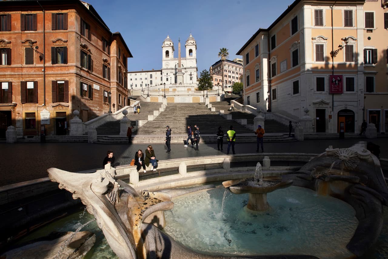 Dos personas en la fuente de Barcaccia, cerca de la Plaza de España casi vacía, en Roma.