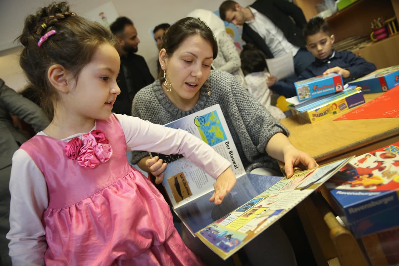 BERLIN, GERMANY - DECEMBER 16: Xenia, 5, and her mother, both from Moldova page through a book in German about animals during the presentation of a new initiative to help children of refugees learn to read German at a shelter for migrants and refugees on December 16, 2015 in Berlin, Germany. The initiative, "Reading Start for Refugee Chidlren," is being launched by the German Ministry of Education and Research. Germany is expected to receive over one million migrants seeking asylum in 2015 and is seeking a rapid integraiton of the newcomers into society and the job market, for which language instruction is a crucial component. (Photo by Sean Gallup/Getty Images)