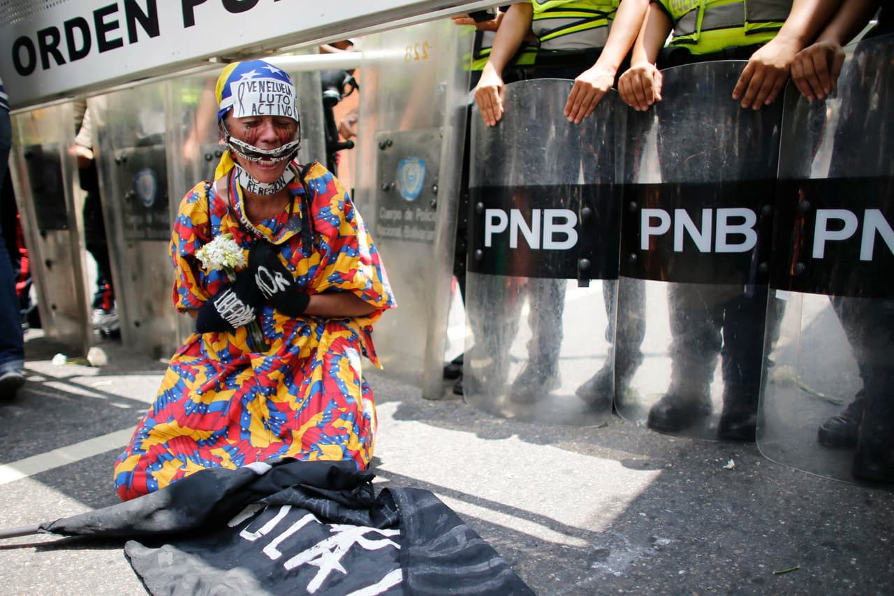 Vestida con atuendos indígenas, ella protesta frente a un piquete de la Policía Nacional Bolivariana. 6 de mayo de 2017.
