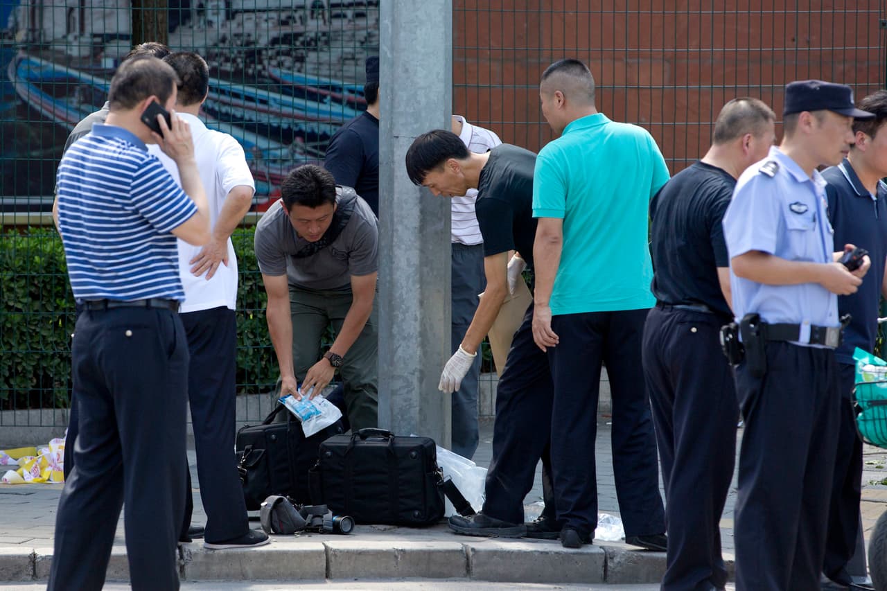 Los expertos recogen las muestras del pequeño artefacto explosivo que detonó un hombre frente a la embajada de EEUU en Pekín.