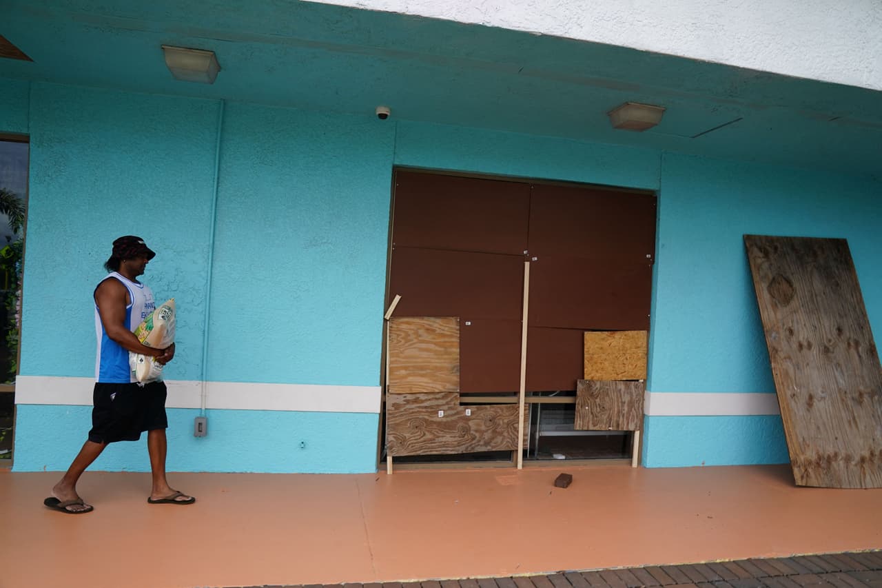 Este hombre lleva una bolsa de arena a su restaurante para protegerse de las inundaciones en Clearwater Beach, Florida.