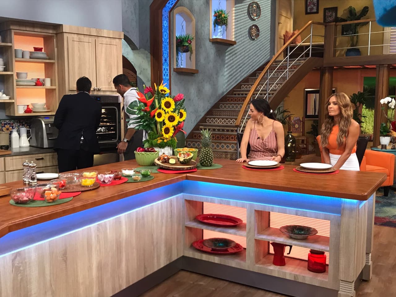 Un guapo colombiano y un guapo venezolano prepararando unos envueltos de pollo y de carne para todas en el estudio.